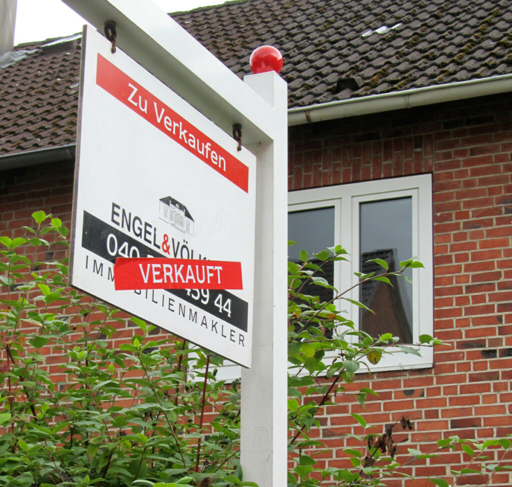 Ein Haus, davor das Schild eines Immobilienmaklers mit den Vermerk "Verkauft"