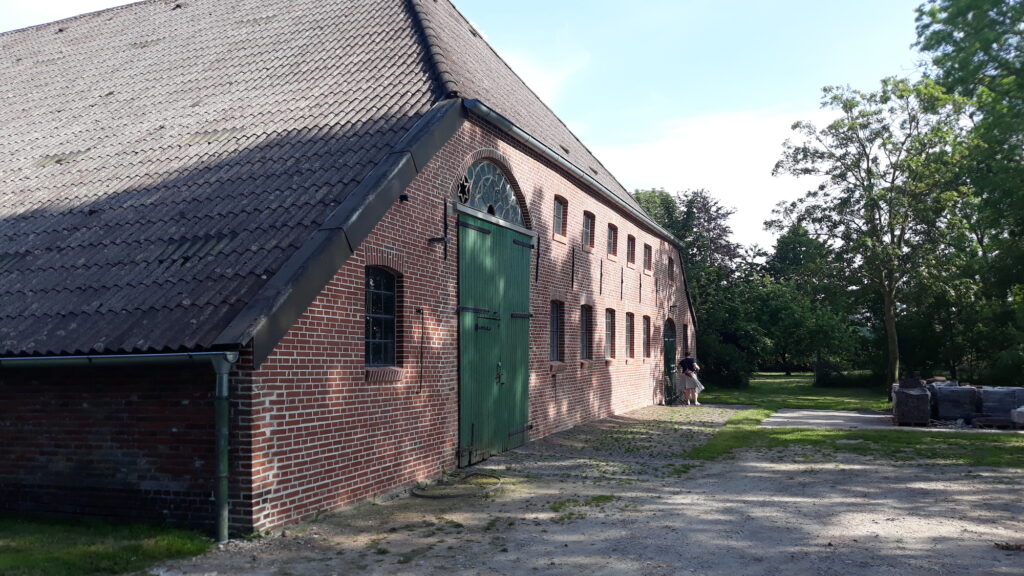 Zu sehen ist der Hintereingang des Kleinen Schulenburger Polders, einem ehemaligen Hof in Niedersachsen, bei Sonnenschein.