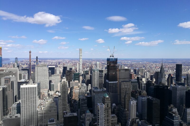 Ein Ausblick über die Wolkenkratzer von New York City unter blauem Himmel, aufgenommen vom Empire State Building aus