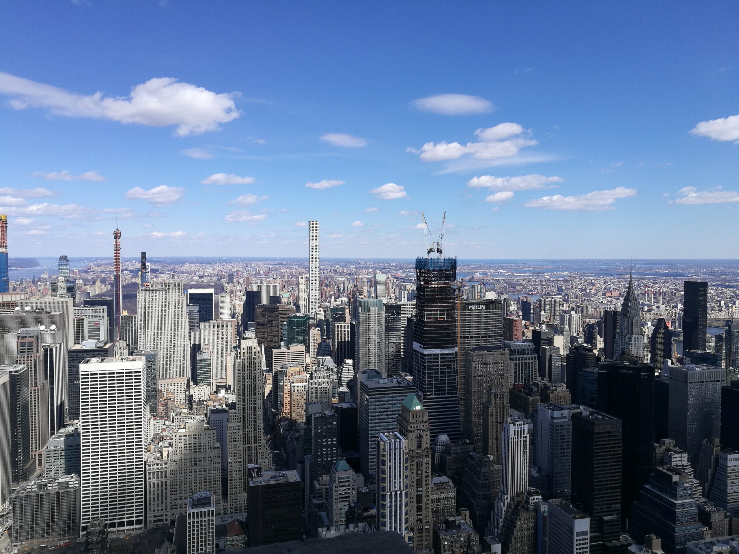 Ein Ausblick über die Wolkenkratzer von New York City unter blauem Himmel, aufgenommen vom Empire State Building aus