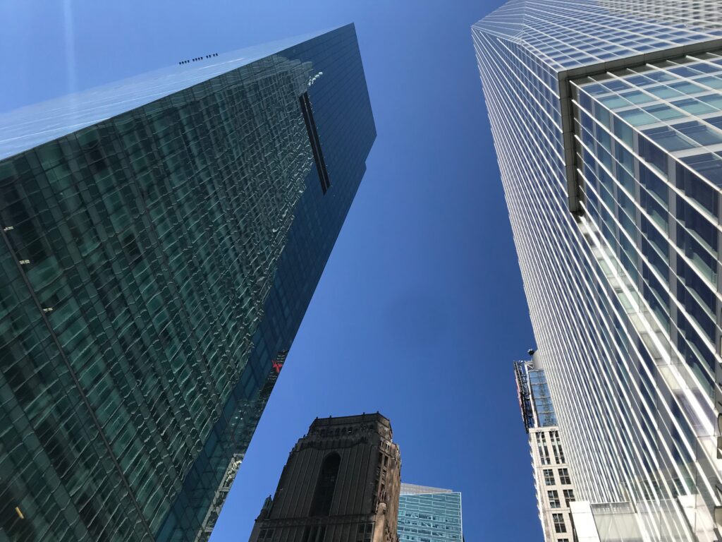 Mehrere Hochhäuser mit Glasfassade in New York vor blauem Himmel.