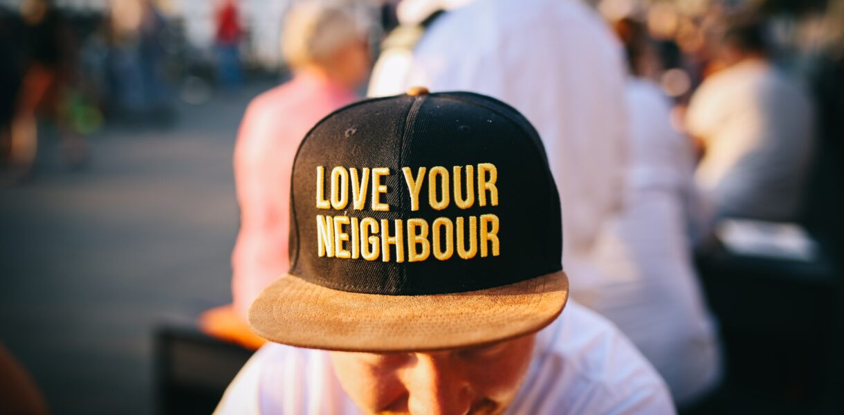 Ein junger Mann trägt ein Cap auf dem steht "Love your neighbours"