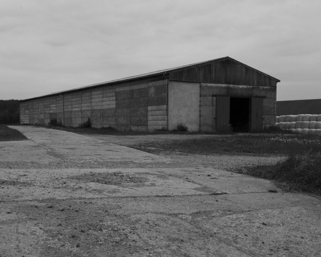 Schwarz-Weiss-Aufnahme von einer alten Industriehalle aus Betonplatten.