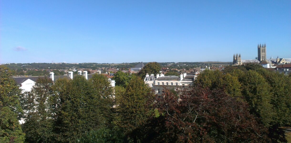 Ein Blick von oben auf Canterbury mit viel Grün und den Türmen der Kathedrale