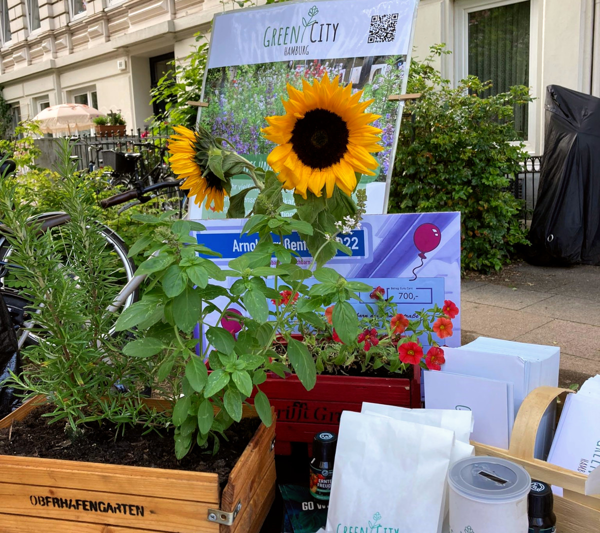 Ein Stand des Vereins Green City Hamburg. Zu sehen sind verschiedene Pflanzen, unter anderem zwei Sonnenblumen, Saattütchen und ein Plakat mit dem Namen.