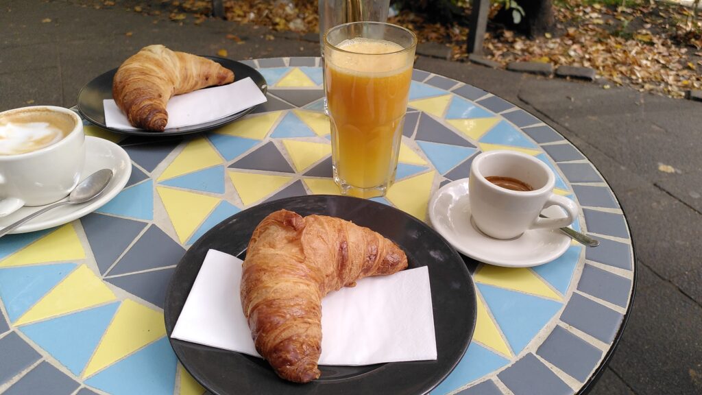 Ein Café-Tisch mit zwei Kaffees, zwei Croissants und einem Orangensaft